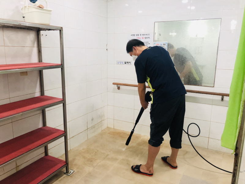 복지관 직원이 샤워장을 청소하고 있는 사진입니다.